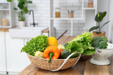 Tahta mutfak tezgahında farklı taze sebzelerle dolu bir sepet.