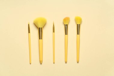 Sarı arka planda değişik stil makyaj fırçaları.