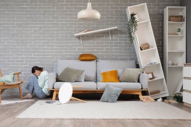 Deprem sırasında oturma odasında kanepede saklanan korkmuş genç bir kadın.