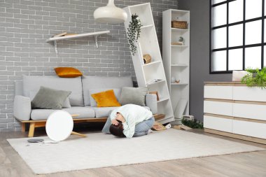 Deprem sırasında oturma odasında saklanan korkmuş genç bir kadın.