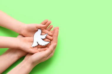 Yeşil arka planda kağıt güvercin olan çocuk ve kadın elleri. Uluslararası Barış Günü