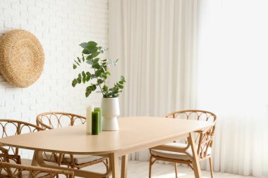 Odada okaliptüs dalları olan sandalyeler ve yemek masaları.