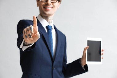 Tablet bilgisayarlı genç işadamı gri arkaplanda sanal ekran kullanıyor, yakın plan