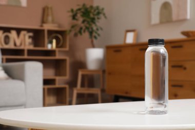 Oturma odasındaki masada bir şişe su, yakın plan.