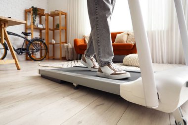 Ofisteki koşu bandında antrenman yapan genç adam, yakın plan.