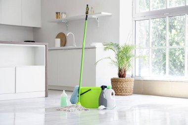 Evde kovayla paspas ve farklı temizlik malzemeleri var.