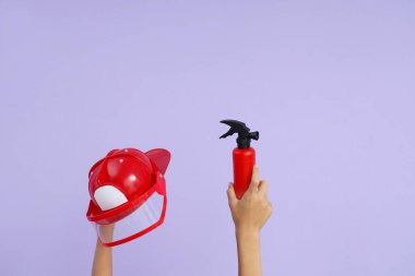 Çocuk itfaiyeci kaskı ve oyuncak söndürme ile leylak arka planda