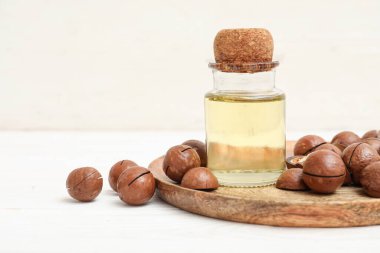 Bir şişe macadamia yağı ve açık ahşap masada fındık.