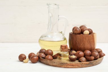 Makadamia yağı ve açık ahşap arka planda fındıklar.