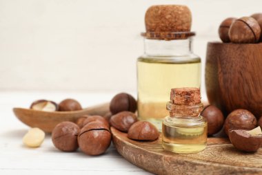 Makadamia yağı şişeleri ve açık ahşap masada fındıklar, yakın plan.