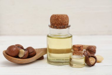 Bir şişe macadamia yağı ve açık ahşap masada fındık.