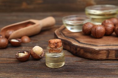 Bir şişe Macadamia yağı ve ahşap masada fındık.