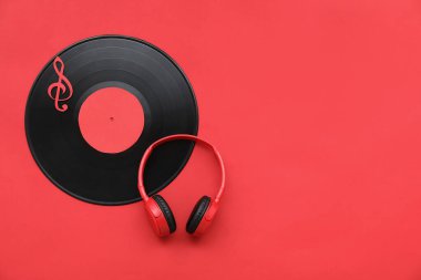 Kırmızı arka planda modern kulaklıklar ve vinil disk