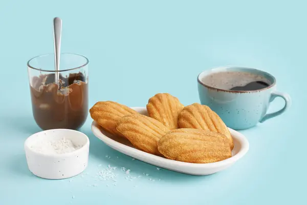 stock image Plate with delicious madeleines, cup of coffee and chocolate paste on blue background