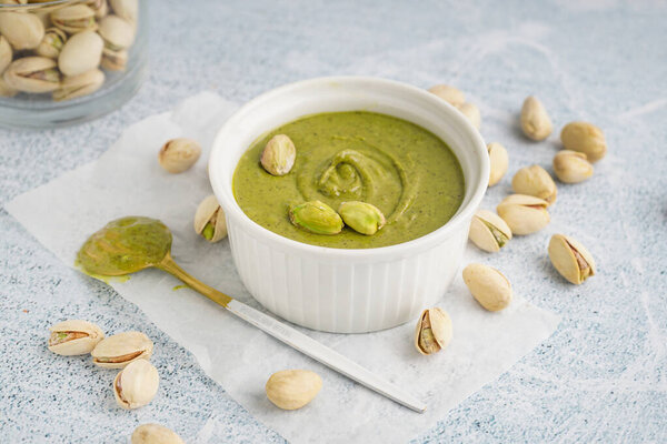 Чаша и ложка с фисташковой пастой на белом фоне гранжа
