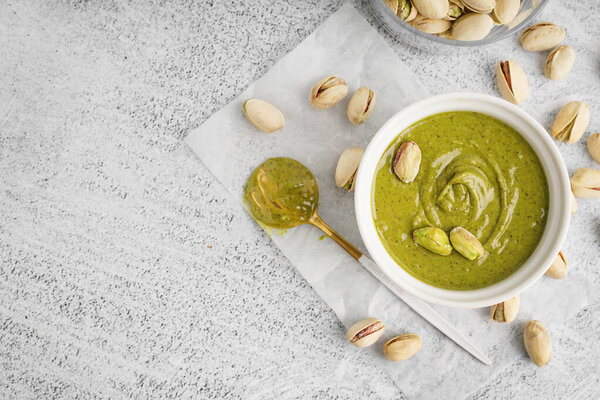 Чаша и ложка с фисташковой пастой на белом фоне гранжа