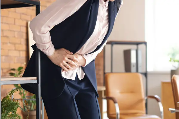 stock image Young businesswoman suffering from severe abdominal pain in office, closeup