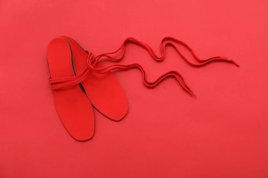 Kırmızı arka planda bir çift ortopedik taban ve ayakkabı bağcığı.