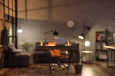 İş yeri, kanepe ve parlak lambalarla karanlık ofisin bulanık görüntüsü