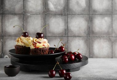 Kirazlı kek tabağı ve gri masada bir kase reçel.