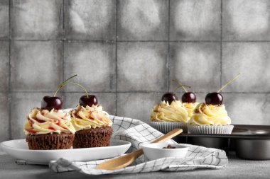 Tabak ve pişirme kalıbı ve gri masadaki vişneli kekler.