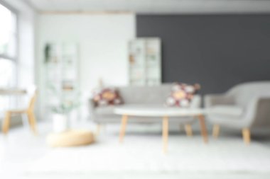 Gri kanepe, koltuk ve raf üniteleriyle oturma odasının bulanık görüntüsü