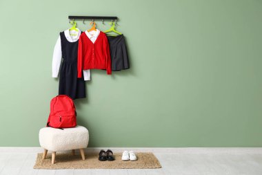 Sırt çantası, ayakkabılar ve renkli duvarda asılı şık okul üniforması.