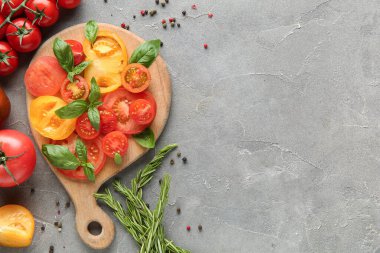 Farklı taze domates, fesleğen, biberiye ve biberiye dilimli ahşap tahta.