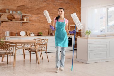 Mutfakta toz bezi ve paspasla genç bir kadın.