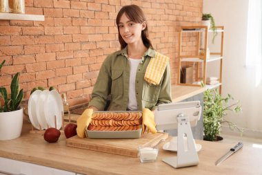 Mutfaktaki masada elmalı turta yiyen genç bir kadın.