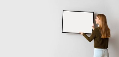 Işık duvarına boş fotoğraf çerçevesi asan bir kadın. Tasarım için pankart