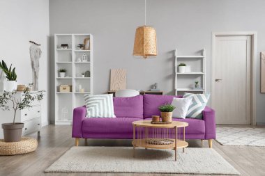 İçinde menekşe kanepe, masa ve raf üniteleri olan bir oturma odası.