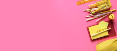 Pembe arka planda farklı okul malzemeleri, metin ve üst görünüm için yer var.