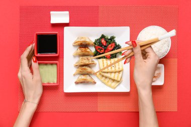 Farklı Çin yemekleri ve kırmızı arka planda yemek çubukları olan kadın elleri.