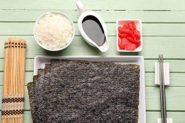 Norveç çarşaflı, pirinçli, zencefilli, soya soslu ve ahşap arkaplanlı suşi aksesuarlı tabak.