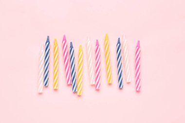Pembe arka planda renkli doğum günü mumları