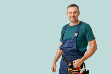 Mavi arka planda alet kemeri olan erkek tamircinin portresi