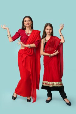 Anne ve kızı sari içinde mavi arka planda dans ediyorlar. Divaly kutlaması