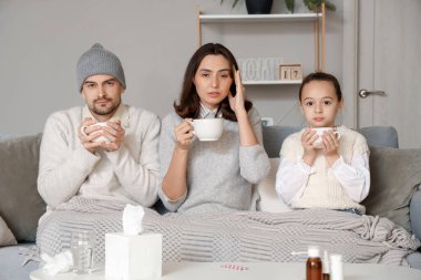 Aile evdeki kanepede sıcak çay içiyor.