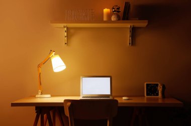 Modern dizüstü bilgisayarı ve gece lambasıyla rahat bir iş yeri.