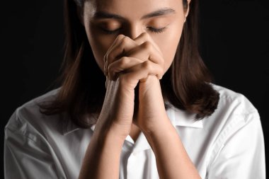 Siyah arka planda dua eden genç kadın, yakın plan.