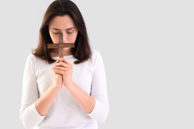 Genç bir kadın arka planda haç ile dua ediyor