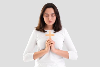 Genç bir kadın arka planda haç ile dua ediyor