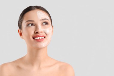 Hafif arka planda yüz maskesi olan genç Asyalı kadın, yakın plan.