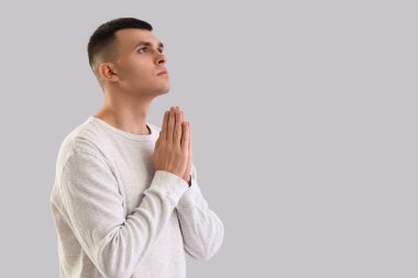 Genç adam gri arka plan üzerinde dua