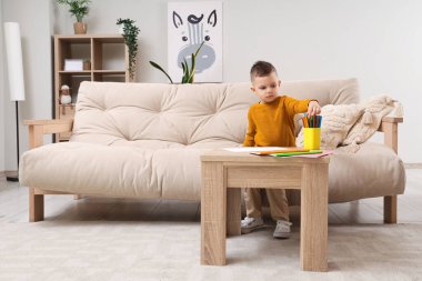 Evdeki masada keçeli kalemlerle çizen sevimli küçük çocuk.