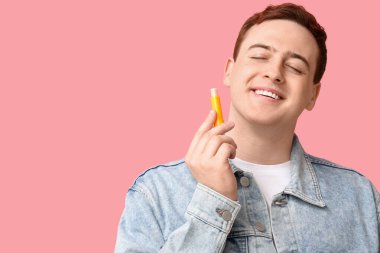 Pembe arka planda dudak merhemi olan yakışıklı bir genç.