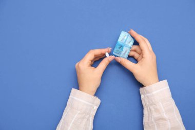 Mavi arka planda haplı kadın elleri