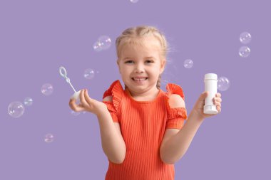 Leylak arkaplanda sabun köpükleri olan mutlu küçük kız.