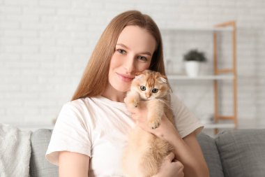 Evde sevimli kedisi olan genç bir kadın, yakın plan.